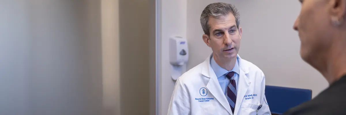 Thoracic surgeon Dr. James Isbell at MSK in New York City, in white lab coat, talks with a patient.
