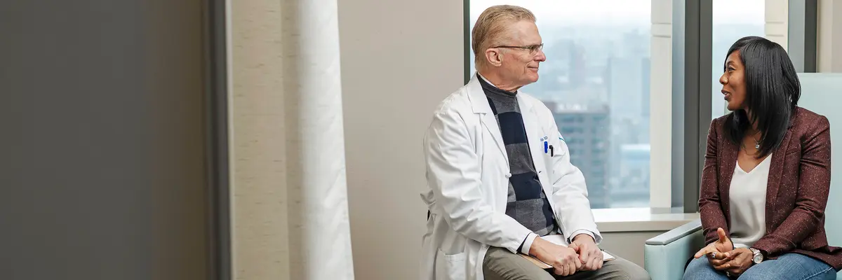 Colorectal surgeon Dr. Philip Paty is sitting and talking with his patient in an exam room at MSK in New York City. 