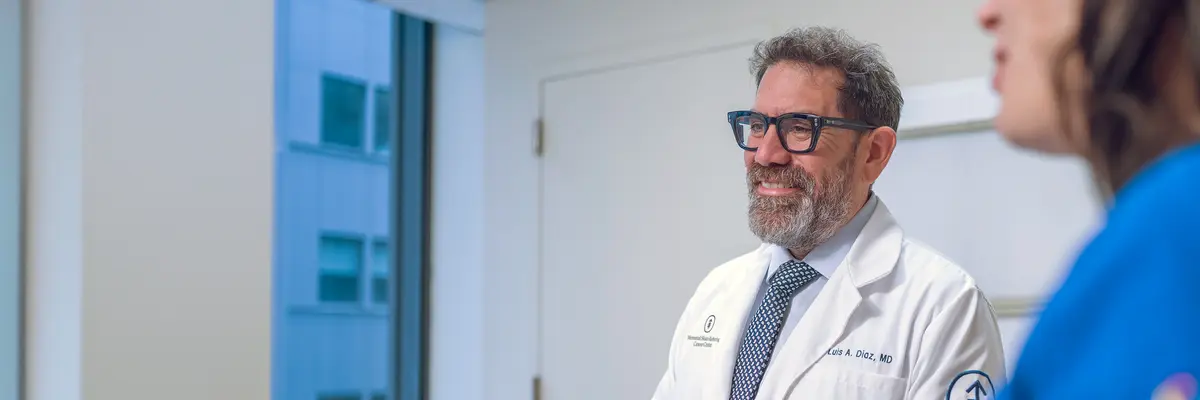 Gastrointestinal medical oncologist Dr. Luis Diaz talks with a colleague in an MSK hallway.