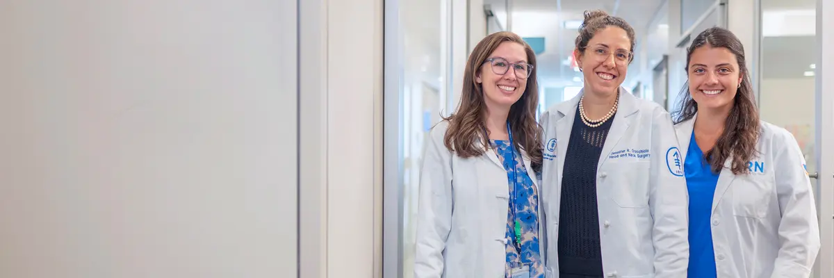 Head and neck surgeon Dr. Jennifer Cracchiolo with two female colleagues stand in a hallway at MSK. 