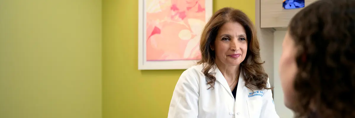 Endocrinologist Dr. Mona M. Sabra, an expert in advanced thyroid cancers, sits with her patient in an MSK exam room.