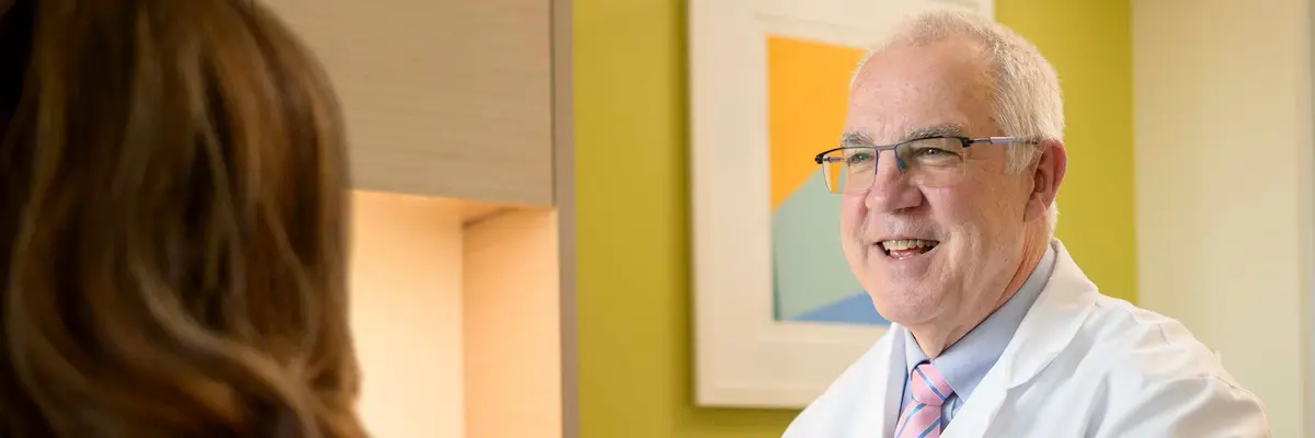Endocrinologist Dr. R. Michael Tuttle talks with a patient as she sits on an exam table. 