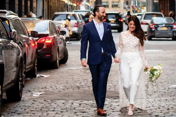 Colon cancer survivor Rebecca Lerner and husband Ian smile and hold hands as they walk on a city street on their wedding day. 