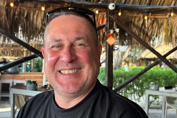 Jon Desjardins, who had immunotherapy at MSK after colorectal cancer surgery, is outdoors and smiling.