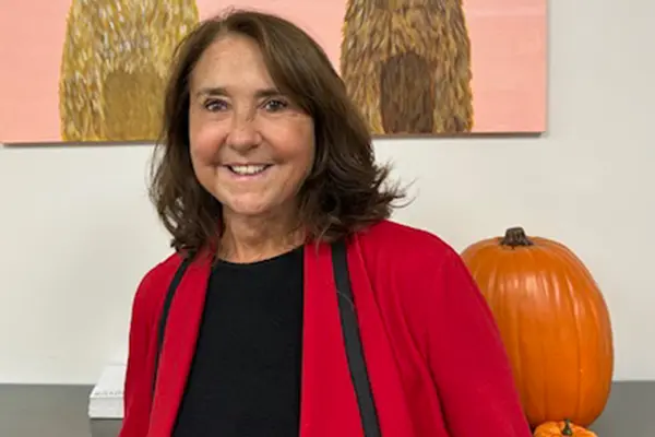 Family photo of Karren Tyler standing in front of a large pumpkin and artwork.