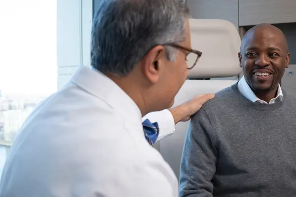 MSK urologic surgeon Dr. Behfar Ehdaie and his patient Eddie are talking in an exam room. 