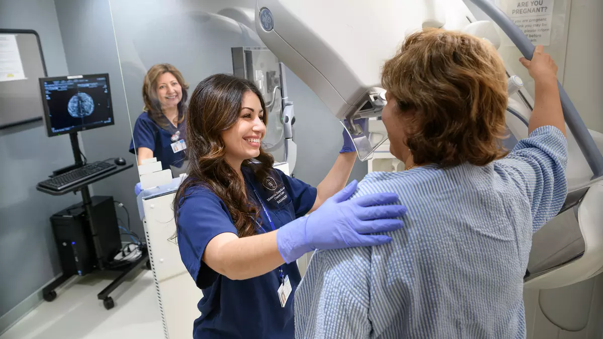 Mammography technologist Elizabeth Mirabile is giving a woman a mammogram. 