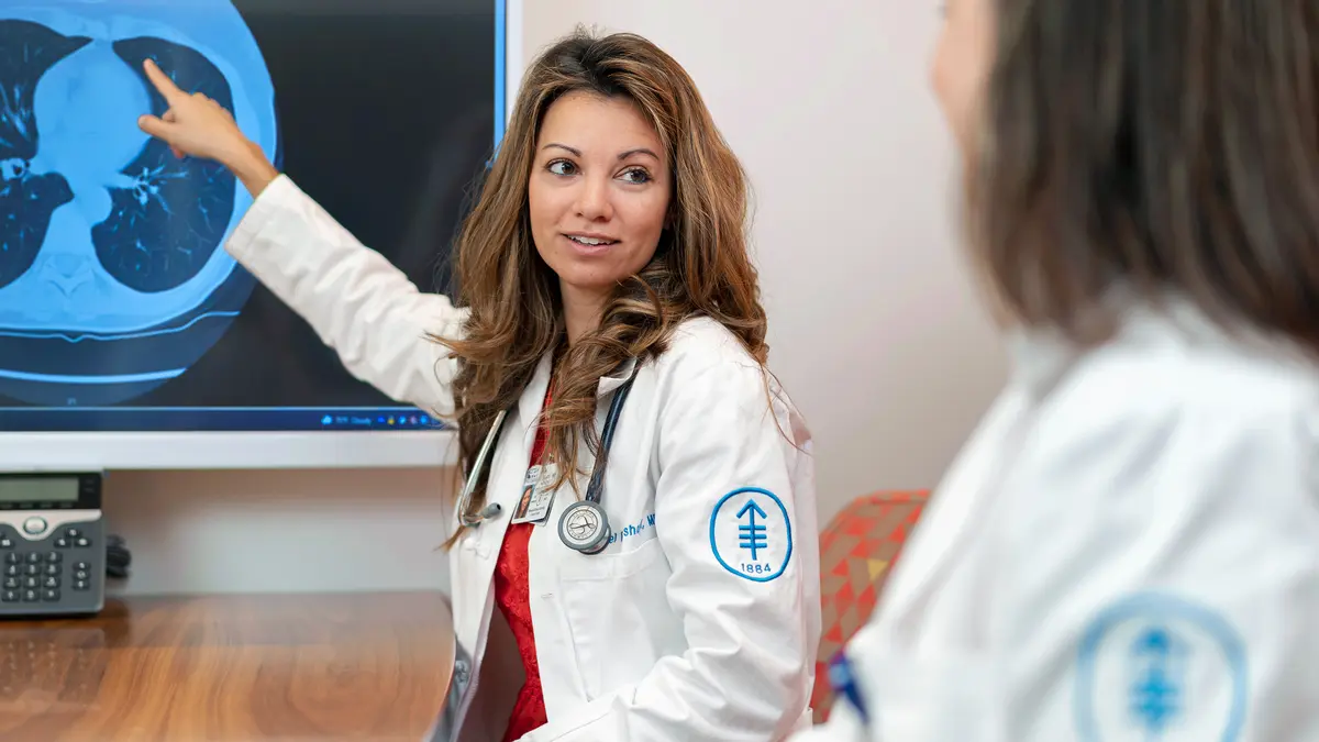 Thoracic medical oncologist Isabel Preeshagul, DO, talks with an RN about a lung cancer scan. 