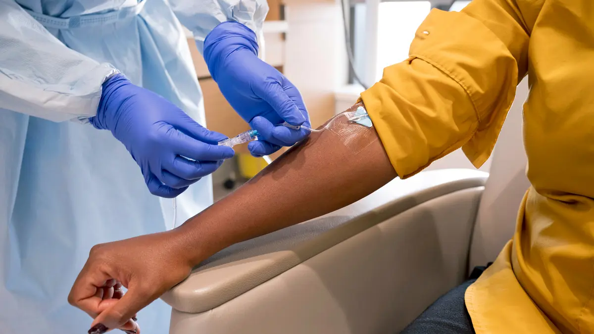 Gloved hands insert an infusion treatment in the forearm of an MSK patient.