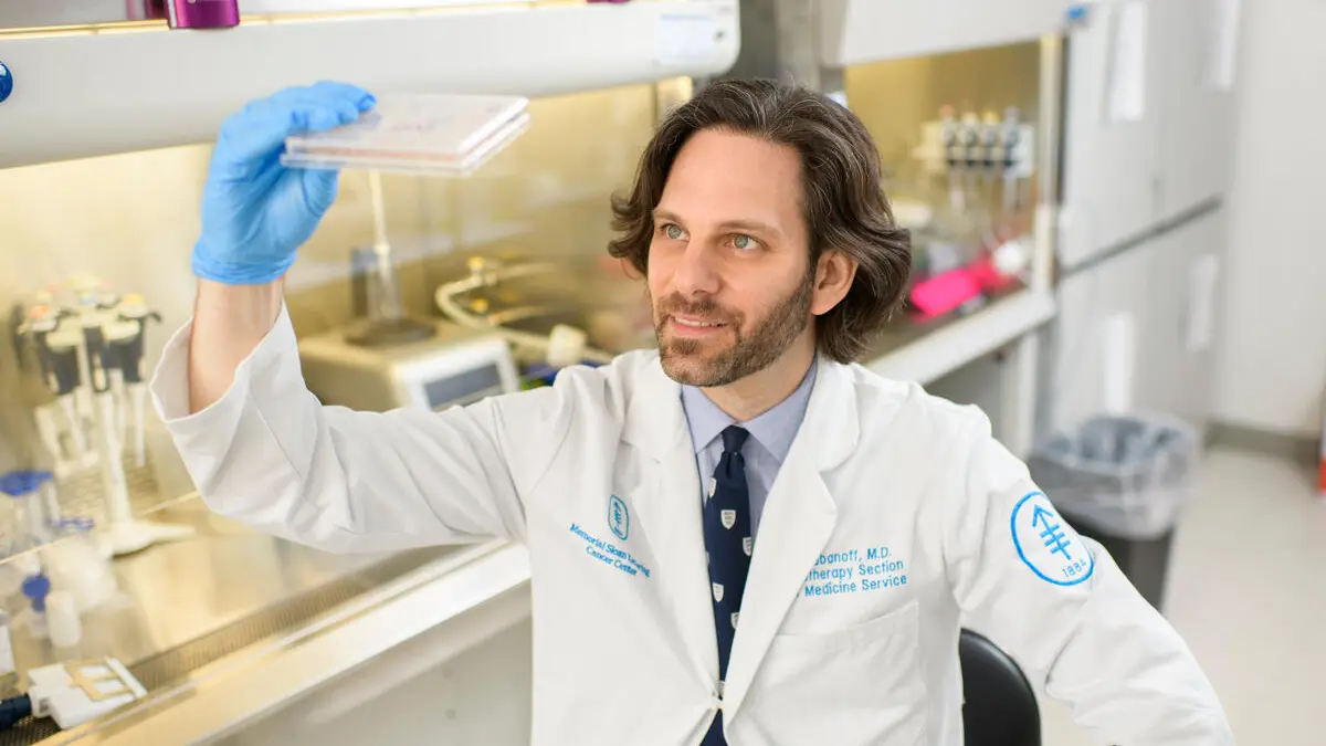 MSK physician-scientist Christopher Klebanoff in lab looking at slide.