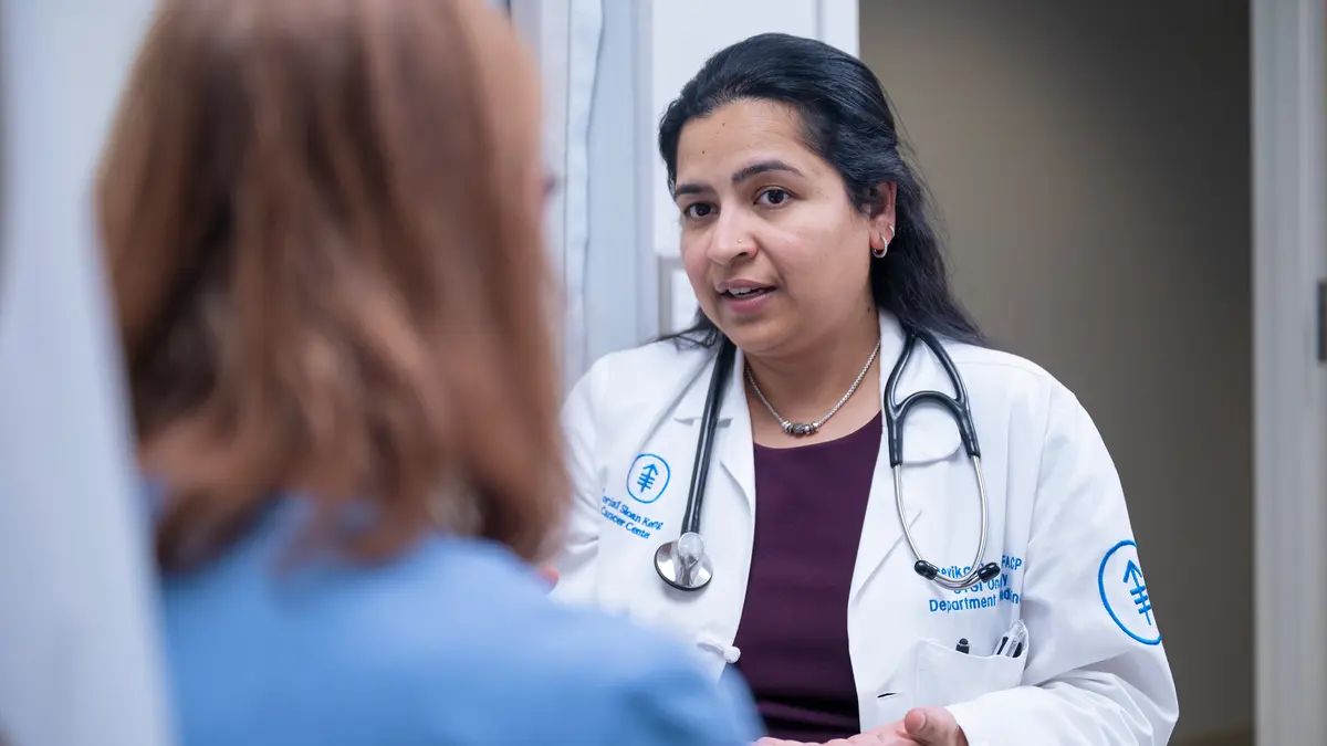 Gastrointestinal medical oncologist Dr. Devika Rao, with a stethoscope, is talking with an MSK patient.