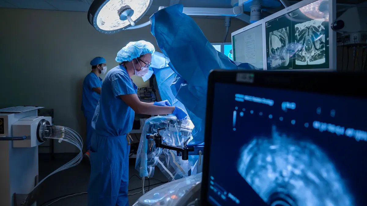 Radiotherapy physicist Brian Leong, wearing protective clothing, is working with equipment in MSK’s brachytherapy suite. 