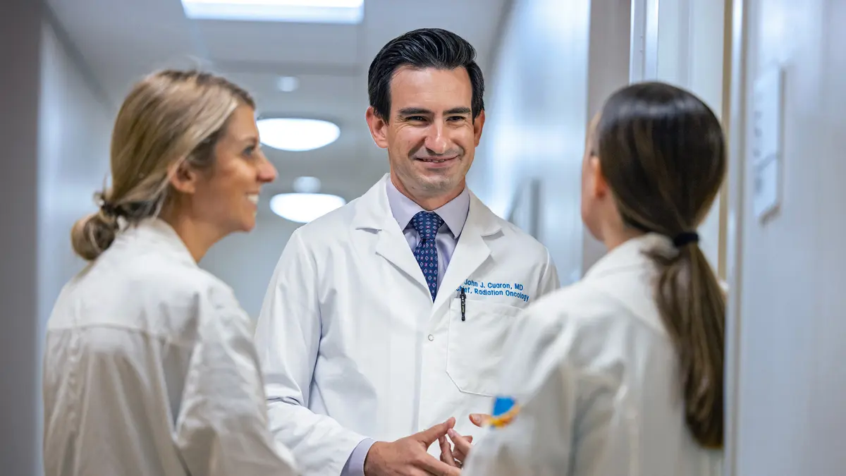 Dr. John Cuaron and nurses Kristina Boyce and Jacquelyn Kochan talk in a hallway at MSK in Commack, LI. 