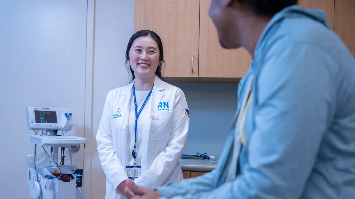 MSK clinical trials nurse Julia Hong is standing in an exam room and talking with her patient. 