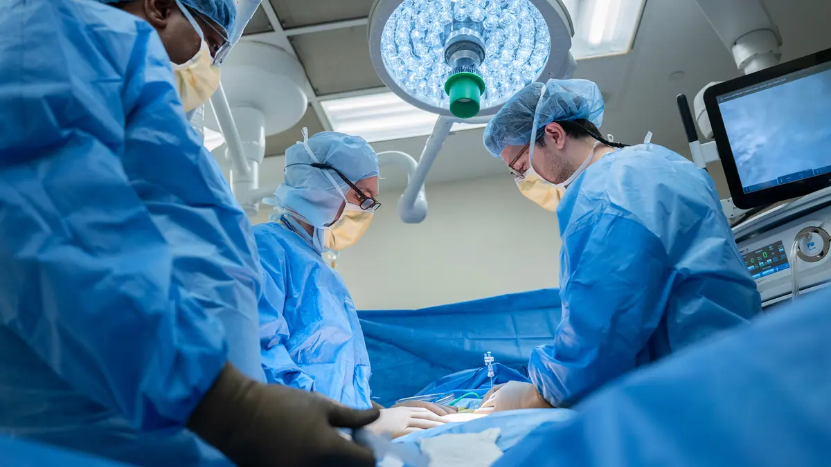 Colorectal surgeon Dr. Garrett Nash, in surgical scrubs, is in an operating room with a surgery team at MSK in New York City. 