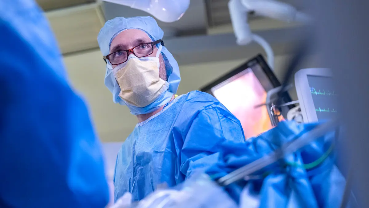Colorectal surgeon Dr. Garrett M. Nash, wearing surgical gear, during robotic surgery.