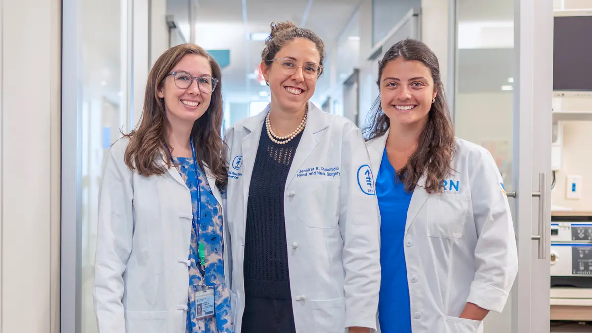 Head and neck surgeon Dr. Jennifer Cracchiolo with two female colleagues stand in a hallway at MSK. 
