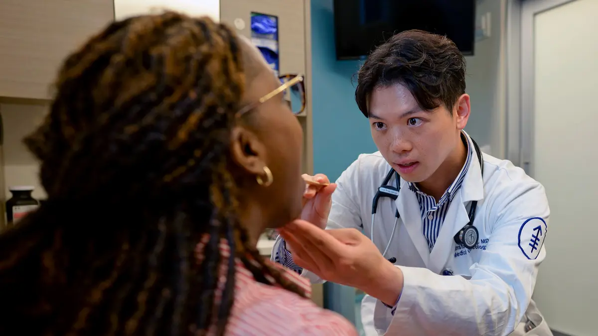 Head and neck medical oncologist Dr. Winston Wong examines the throat of a patient. 