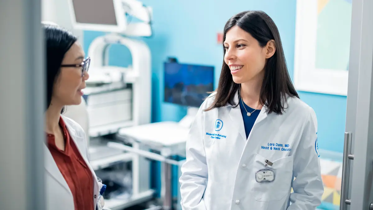 Medical oncologist Dr. Lara A. Dunn talks with Yingzhi Wu, a nurse practitioner, in an exam room. 