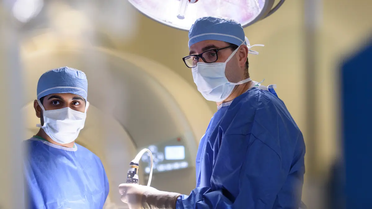 Head and neck surgeon Dr. Marc A. Cohen, wearing surgical gear, in surgery with another care team member. 