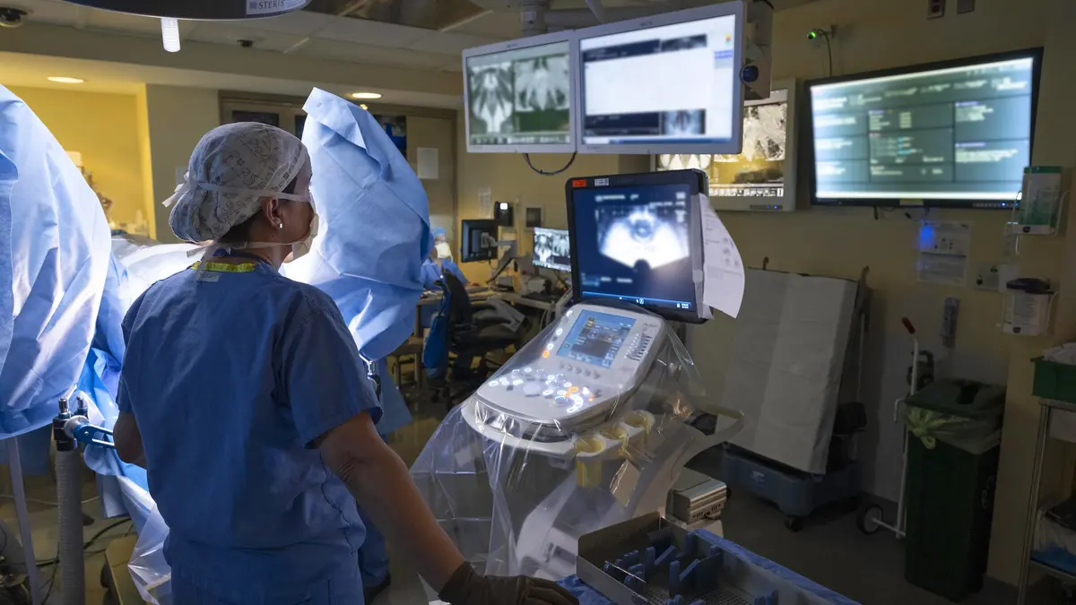 Dr. Kollmeier, dressed in protective surgical gear, looks at 4 monitors during radiation therapy. 