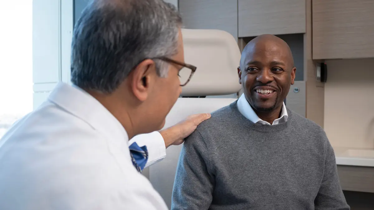Black male patient smiling and talking to cancer doctor.